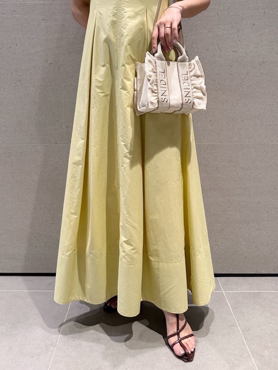 イエロー系のワンピース、ベージュ系のショルダーバッグ、ブラウン系のサンダルを着用したレディースの夏コーディネートの7枚目の写真