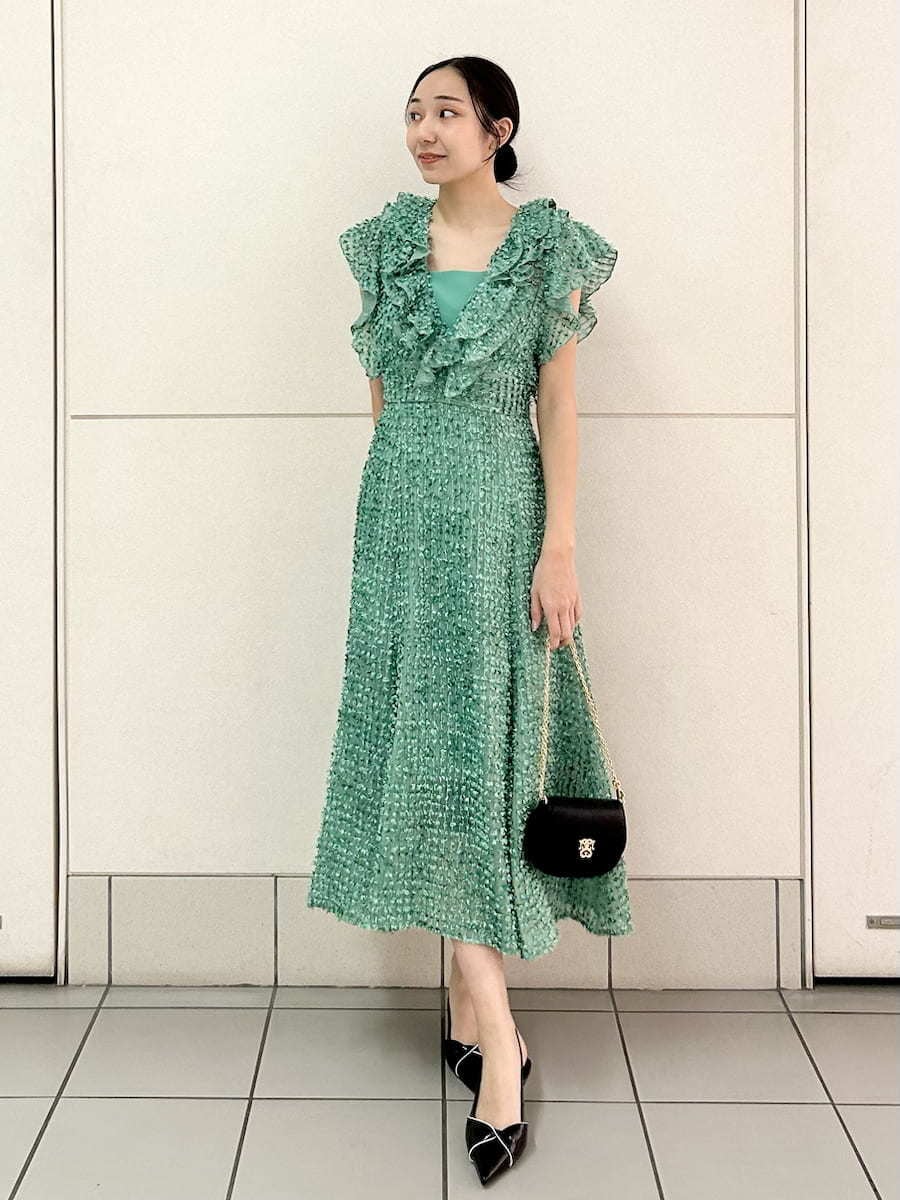 グリーン系のドレス、ブラック系のパンプス、ブラック系のショルダーバッグを着用したレディースの春コーディネートの2枚目の写真