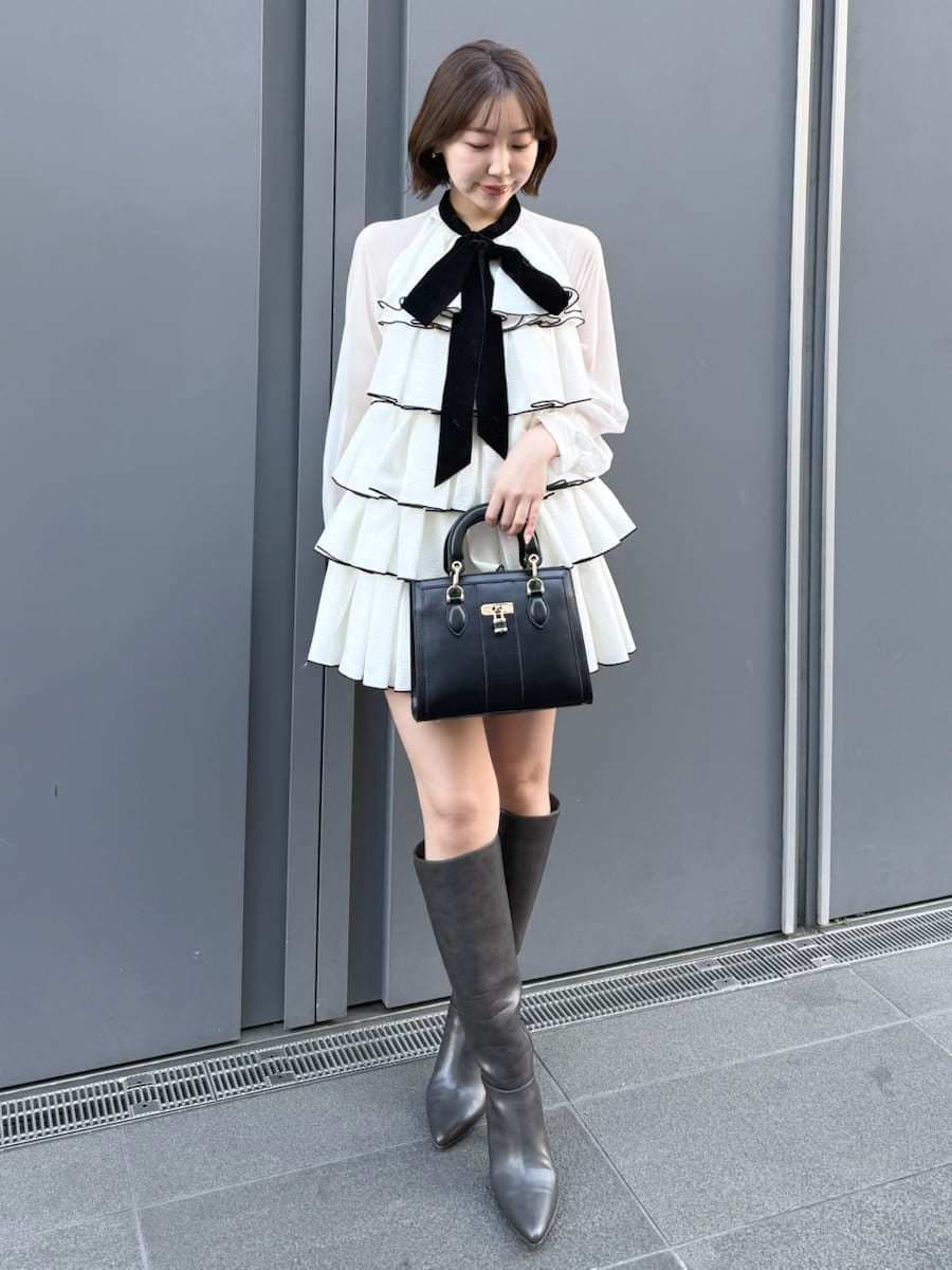ホワイト系のドレス、ブラック系のハンドバッグを着用したレディースの冬コーディネートの3枚目の写真