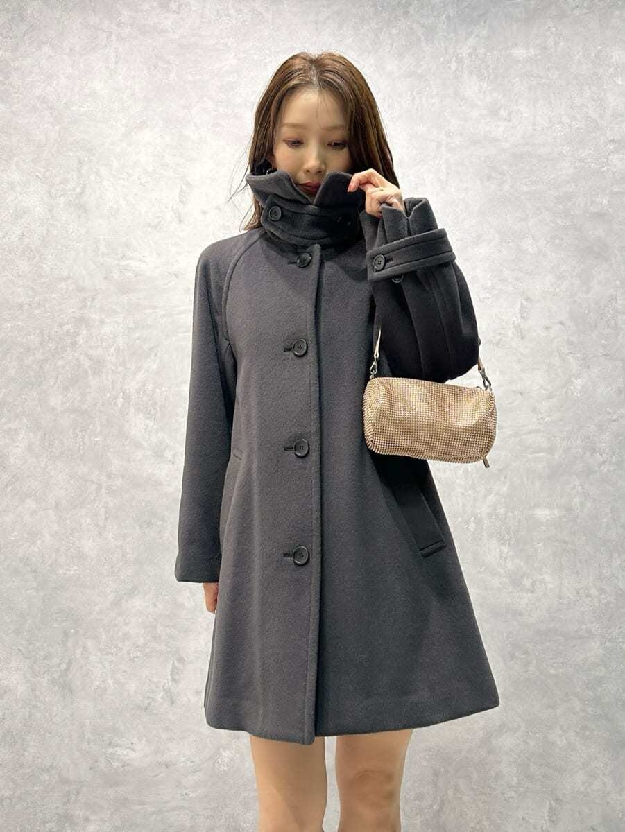 グレー系のステンカラーコート、ホワイト系のワンピースを着用したレディースの秋コーディネートの3枚目の写真