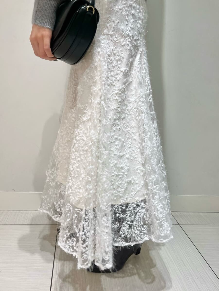 グレー系のニット/セーター、ホワイト系のスカート、ブラック系のハンドバッグを着用したレディースの秋コーディネートの4枚目の写真