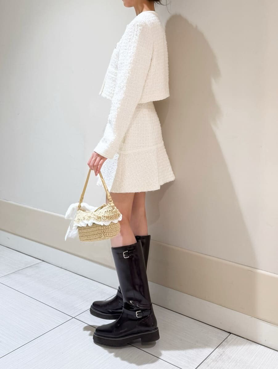 ブラウン系のブーツ、ホワイト系のノーカラージャケット、ホワイト系のスカートを着用したレディースの冬コーディネートの5枚目の写真