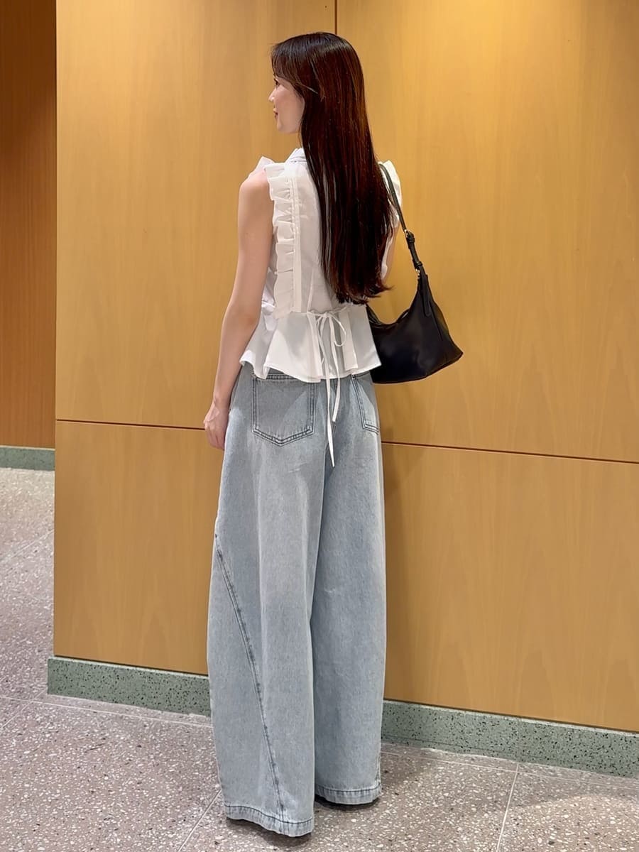 ブルー系のデニムパンツ、ブラック系のサンダル、ブラック系のショルダーバッグを着用したレディースの夏コーディネートの3枚目の写真