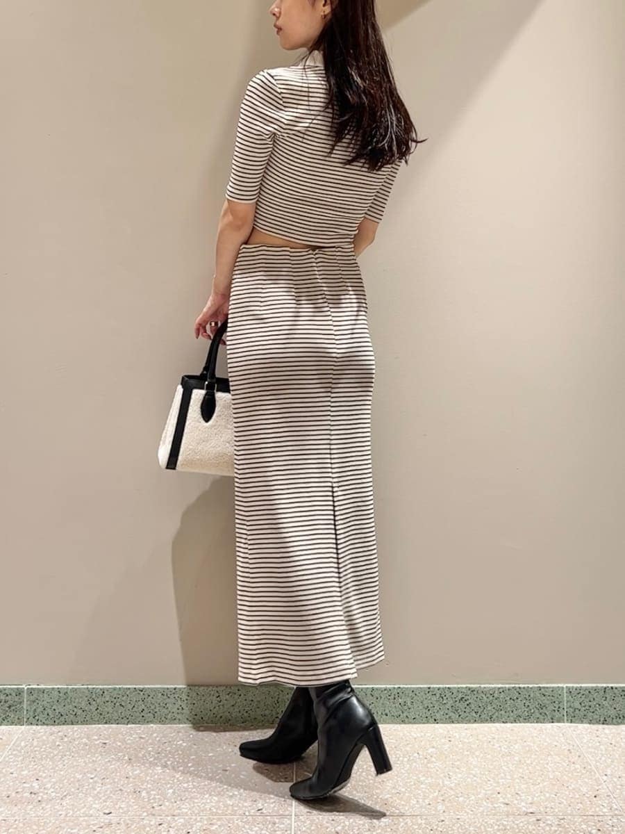 グレー系のブルゾン、ホワイト系のワンピース、ブラック系のハンドバッグを着用したレディースの秋コーディネートの7枚目の写真