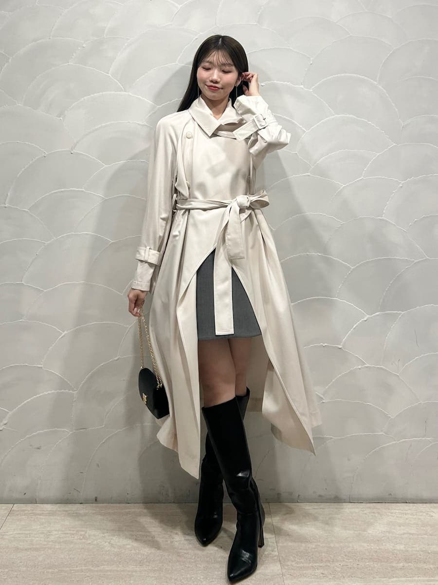 ブラック系のブーツ、ホワイト系のトレンチコート、グレー系のワンピースを着用したレディースの冬コーディネートの5枚目の写真