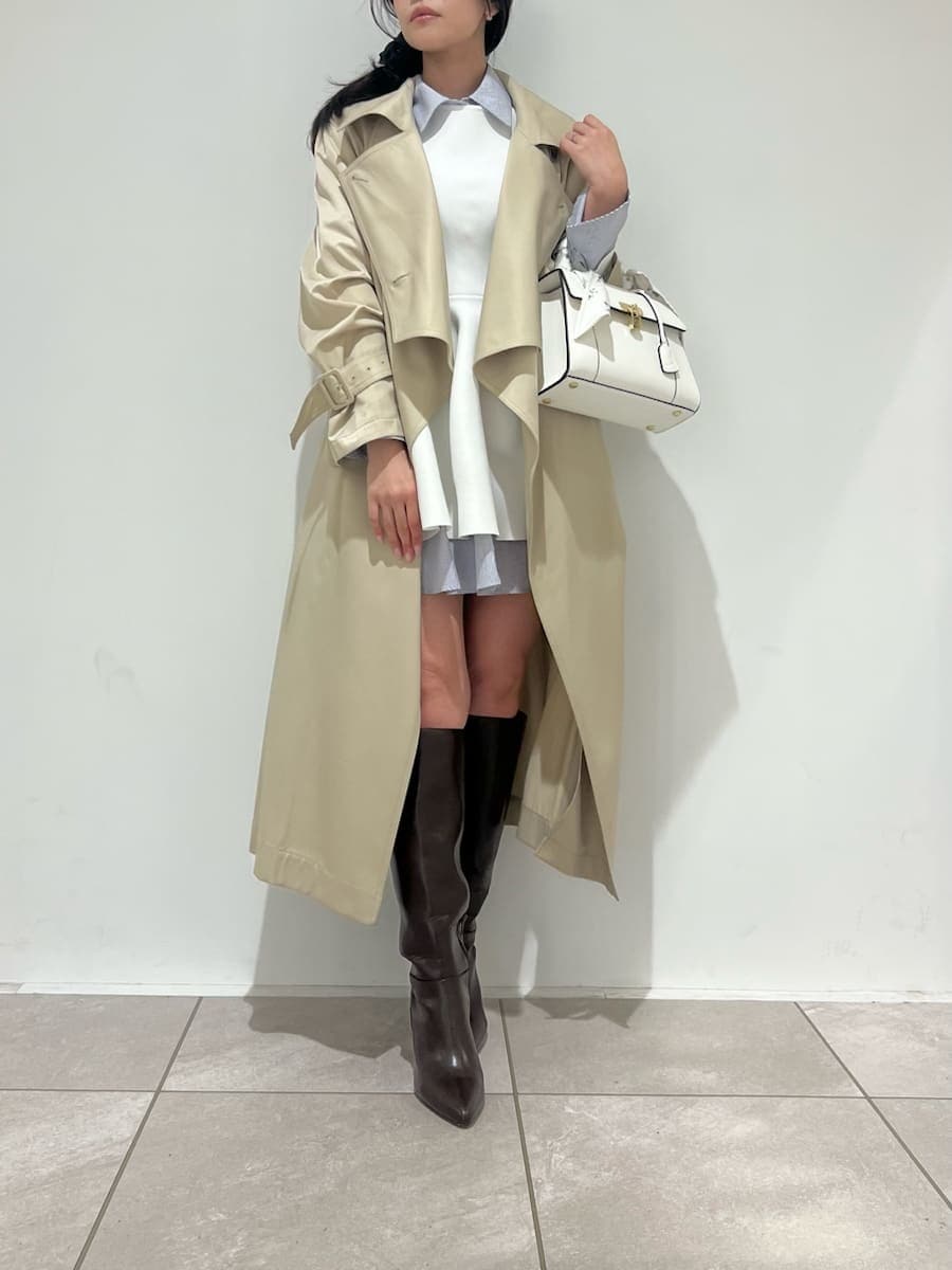ブラウン系のブーツ、ベージュ系のトレンチコート、ホワイト系のハンドバッグを着用したレディースの冬コーディネートの7枚目の写真