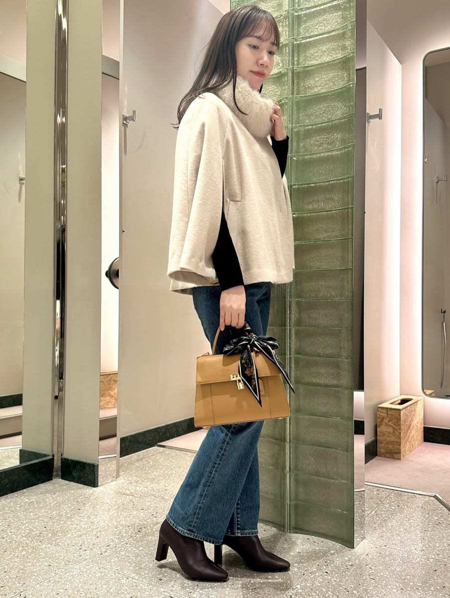 ホワイト系のチェスターコート、ブルー系のデニムパンツを着用したレディースの秋コーディネートの4枚目の写真