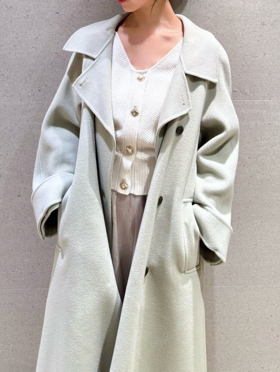 ブラック系のブーツ、ホワイト系のワンピース、グリーン系のチェスターコートを着用したレディースの秋コーディネートの3枚目の写真