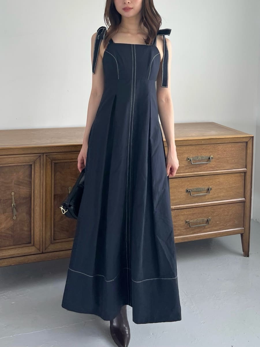 ブラック系のワンピース、ブラック系のハンドバッグ、ブラウン系のブーツを着用したレディースの夏コーディネートの2枚目の写真