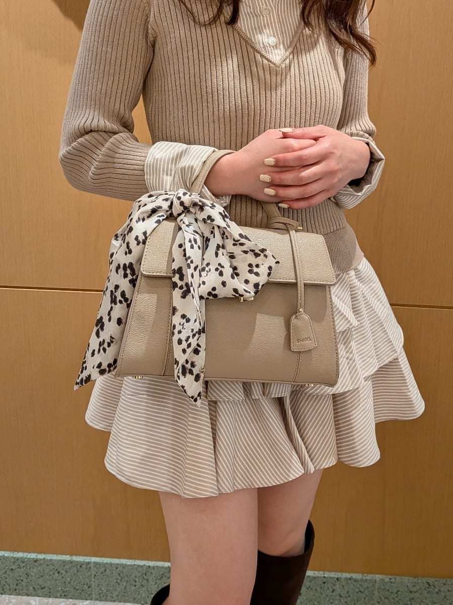ベージュ系のワンピース、ブラウン系のブーツ、ベージュ系のショルダーバッグを着用したレディースの秋コーディネートの6枚目の写真