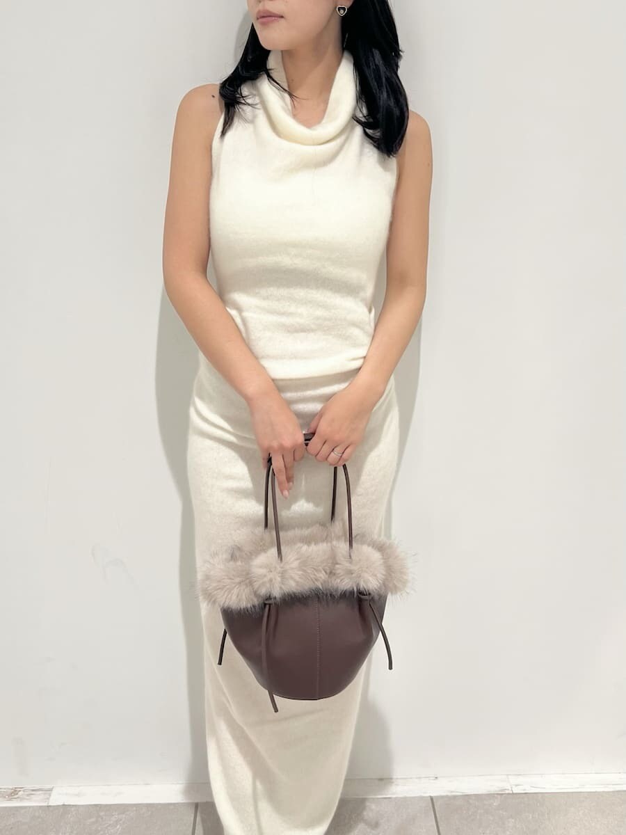 ホワイト系のチェスターコート、ホワイト系のワンピース、ブラウン系のハンドバッグを着用したレディースの冬コーディネートの7枚目の写真