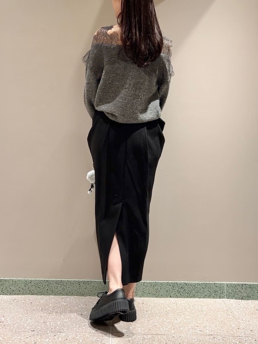 グレー系のニット/セーター、ブラック系のスカート、ブラック系のハンドバッグを着用したレディースの秋コーディネートの2枚目の写真