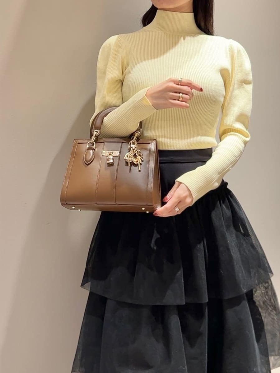 イエロー系のニット/セーター、ホワイト系のムートンコート、ブラック系のスカートを着用したレディースの秋コーディネートの7枚目の写真