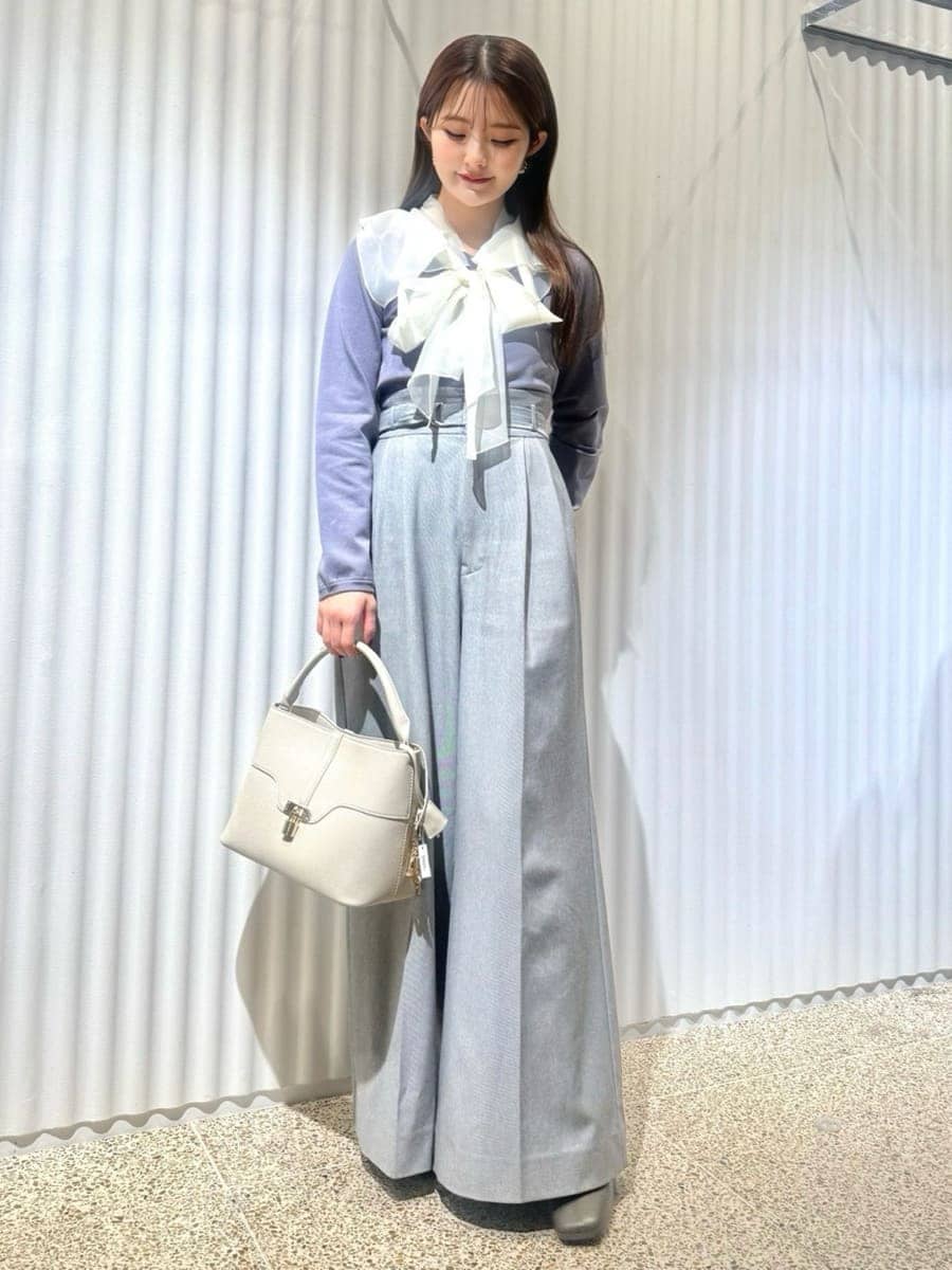 ブラック系のチェスターコート、ブルー系のニット/セーター、ホワイト系のハンドバッグを着用したレディースの冬コーディネートの4枚目の写真