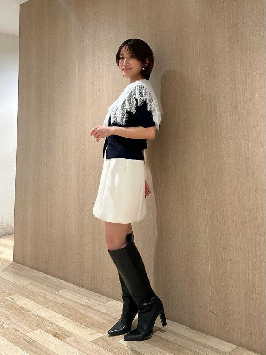 ブラック系のブーツ、ホワイト系のスカート、ブルー系のカーディガン/ボレロを着用したレディースの春コーディネートの3枚目の写真