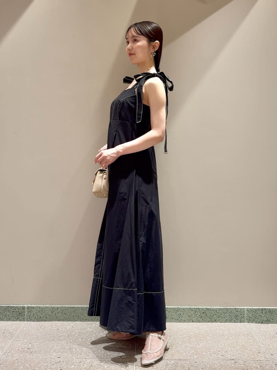 ブラック系のワンピース、ベージュ系のショルダーバッグ、シルバー系のネックレスを着用したレディースの夏コーディネートの2枚目の写真