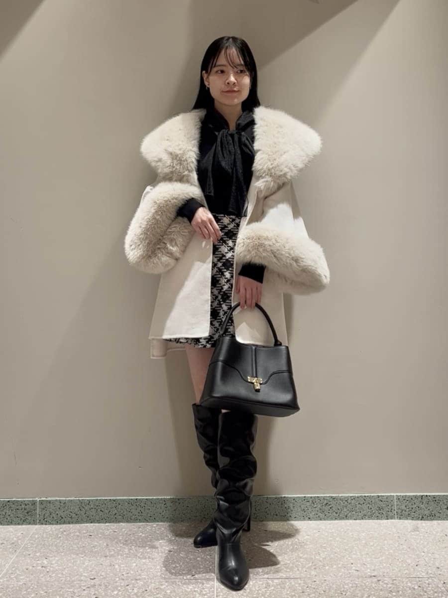ホワイト系のチェスターコート、ブラック系のその他パンツ、ブラック系のハンドバッグを着用したレディースの冬コーディネートの4枚目の写真