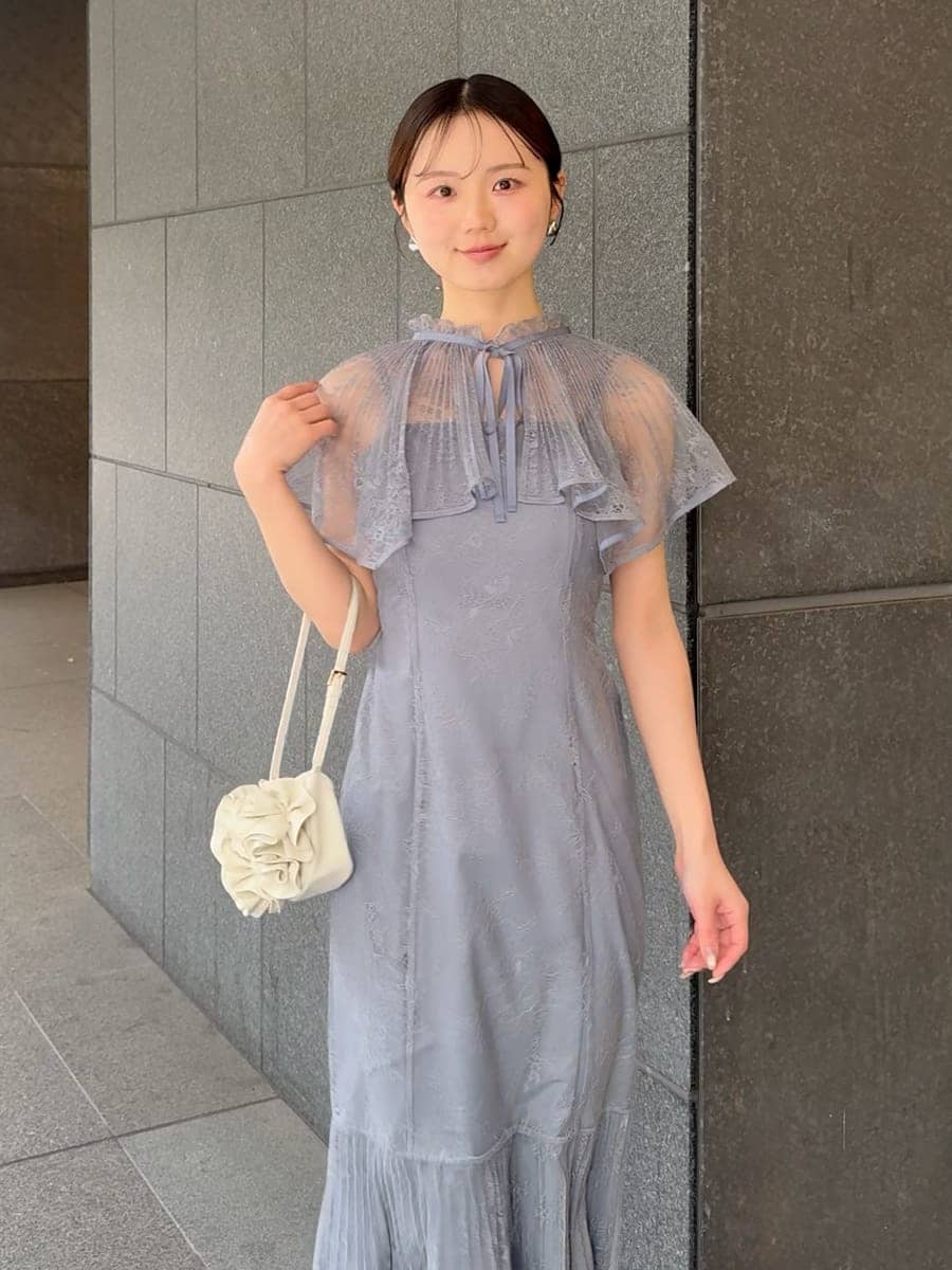 グレー系のドレス、ブラック系のパンプス、ホワイト系のハンドバッグを着用したレディースの春コーディネートの4枚目の写真