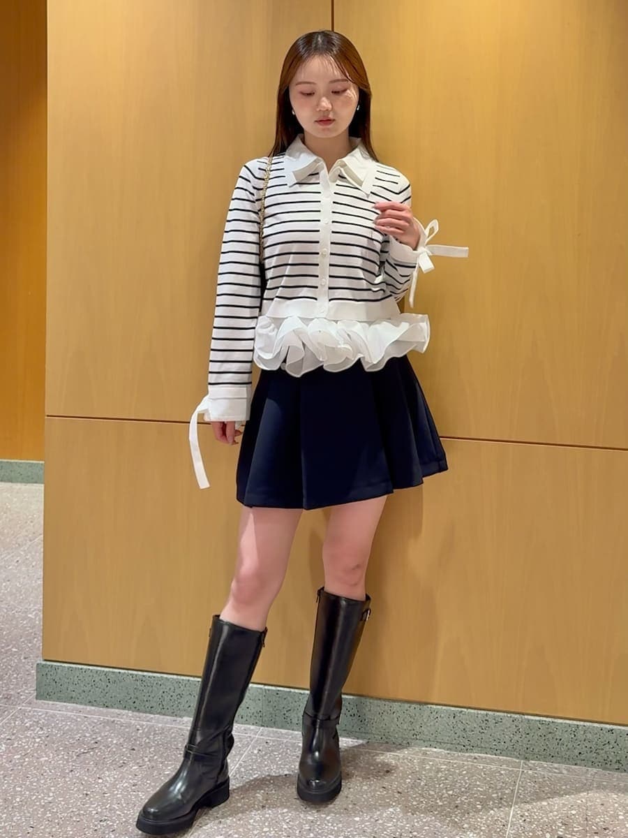 ブラック系のブーツ、ブルー系のスカート、その他のニット/セーターを着用したレディースの冬コーディネートの2枚目の写真