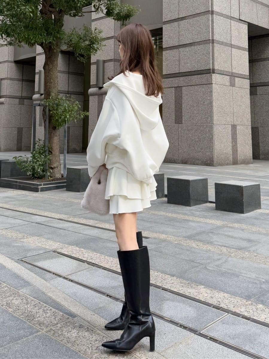 ブラック系のブーツ、ホワイト系のパーカー、ホワイト系のハンドバッグを着用したレディースの冬コーディネートの2枚目の写真