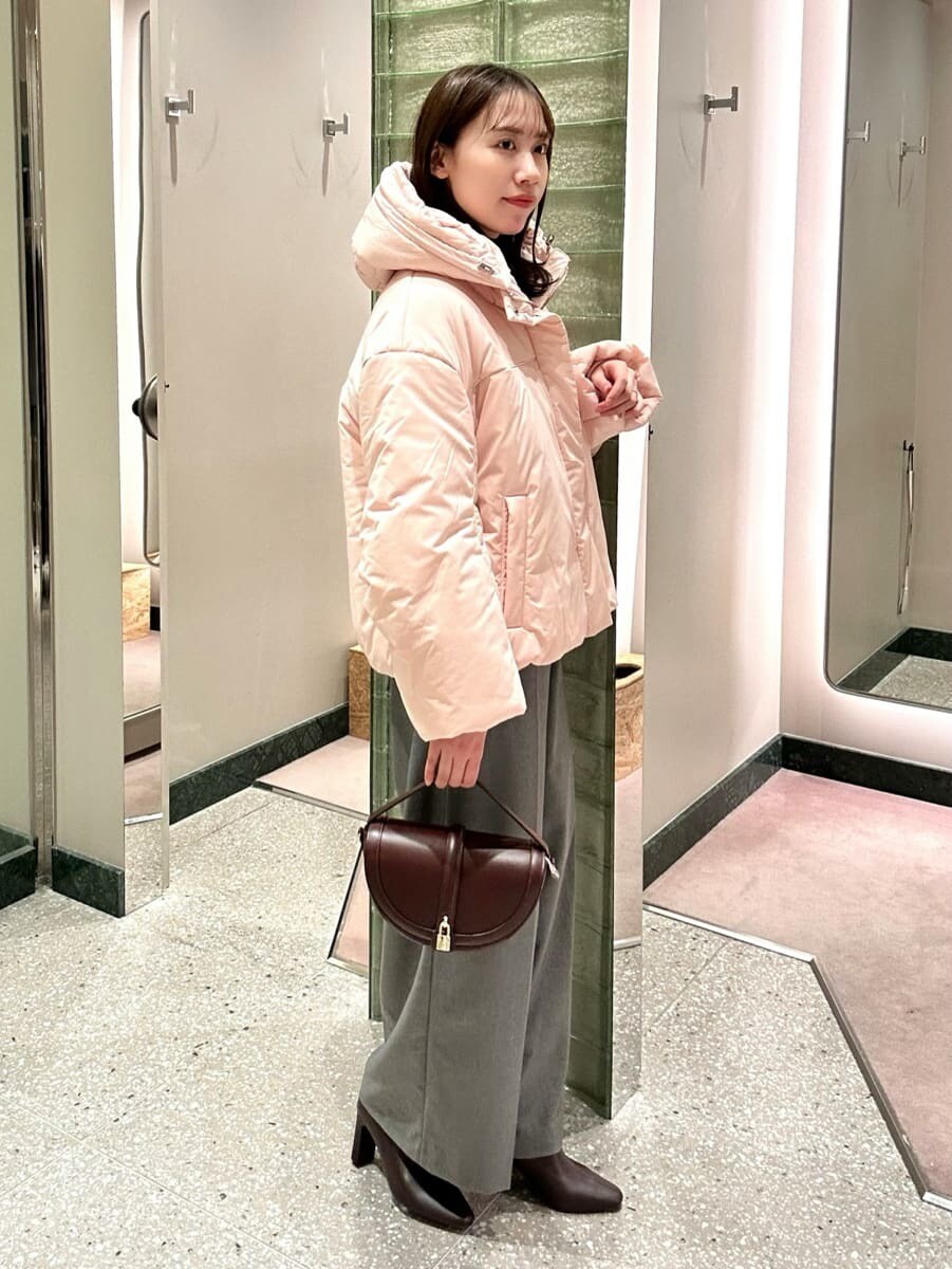 ピンク系のダウンジャケット/コート、ブラック系のニット/セーター、グレー系のスラックスを着用したレディースの秋コーディネートの3枚目の写真