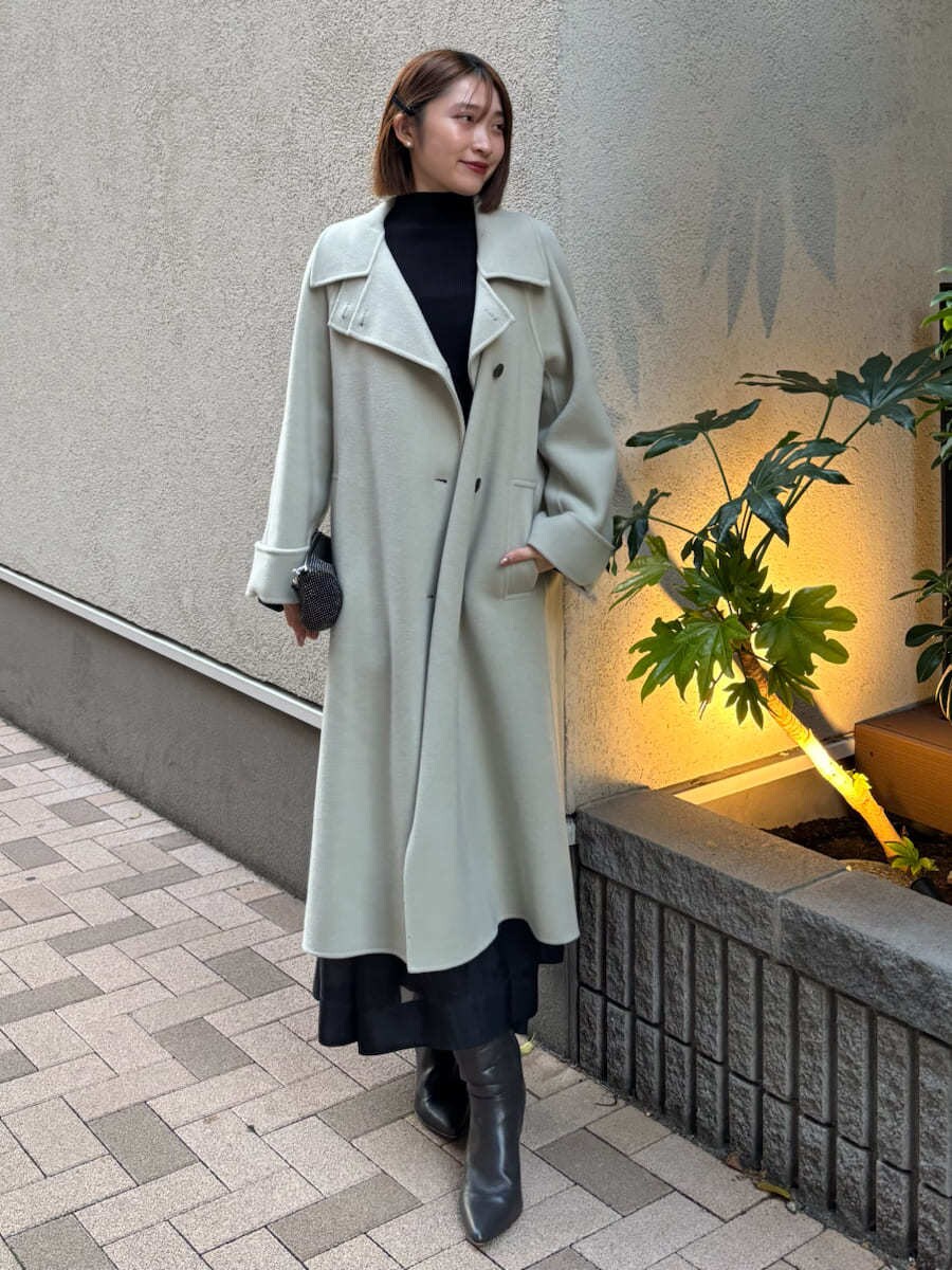 グレー系のブーツ、グリーン系のチェスターコート、ブラック系のワンピースを着用したレディースの秋コーディネートの2枚目の写真