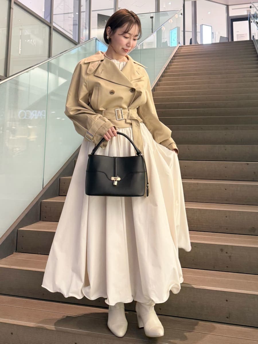 ベージュ系のトレンチコート、ホワイト系のスカート、その他のニット/セーターを着用したレディースの冬コーディネートの10枚目の写真