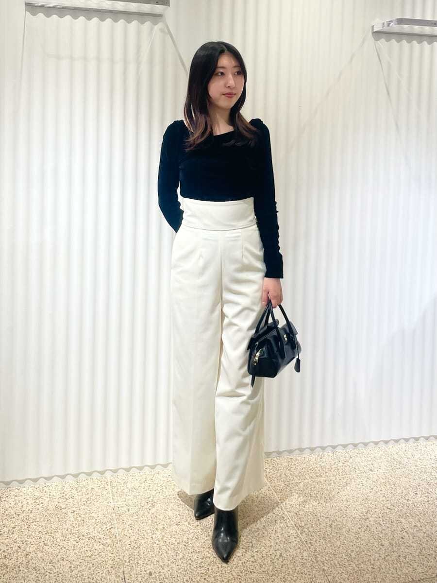 ベージュ系のチェスターコート、ブラック系のTシャツ/カットソー、ホワイト系のスラックスを着用したレディースの秋コーディネートの3枚目の写真