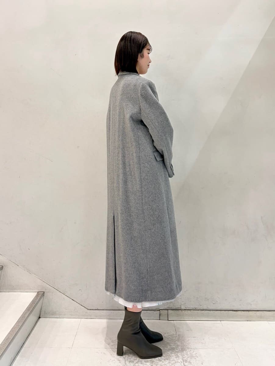 グレー系のワンピース、グレー系のチェスターコート、ゴールド系のイヤリングを着用したレディースの冬コーディネートの6枚目の写真