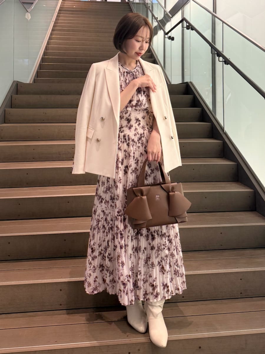 ピンク系のワンピース、ホワイト系のテーラードジャケット、ブラウン系のハンドバッグを着用したレディースの冬コーディネートの2枚目の写真