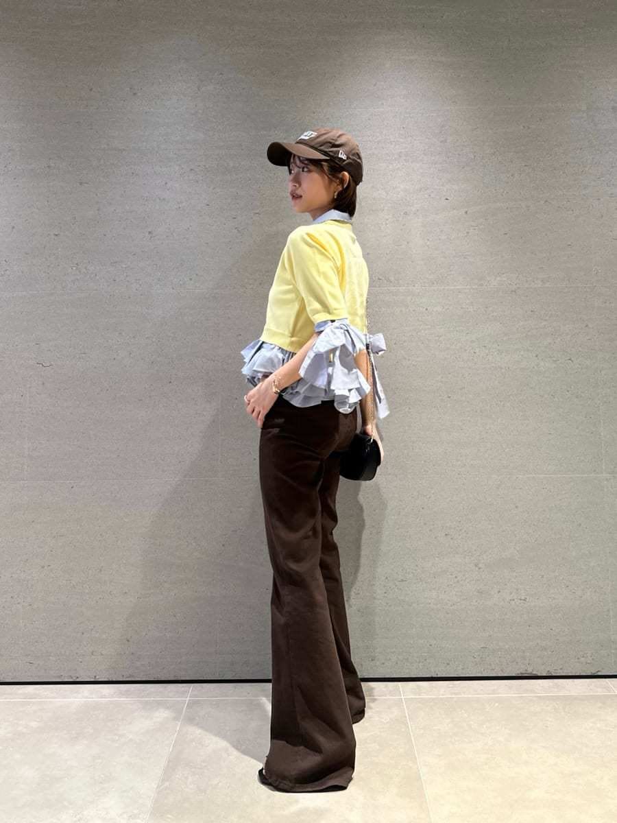 ブラック系のショルダーバッグ、ブラウン系のデニムパンツ、イエロー系のニット/セーターを着用したレディースの春コーディネートの2枚目の写真