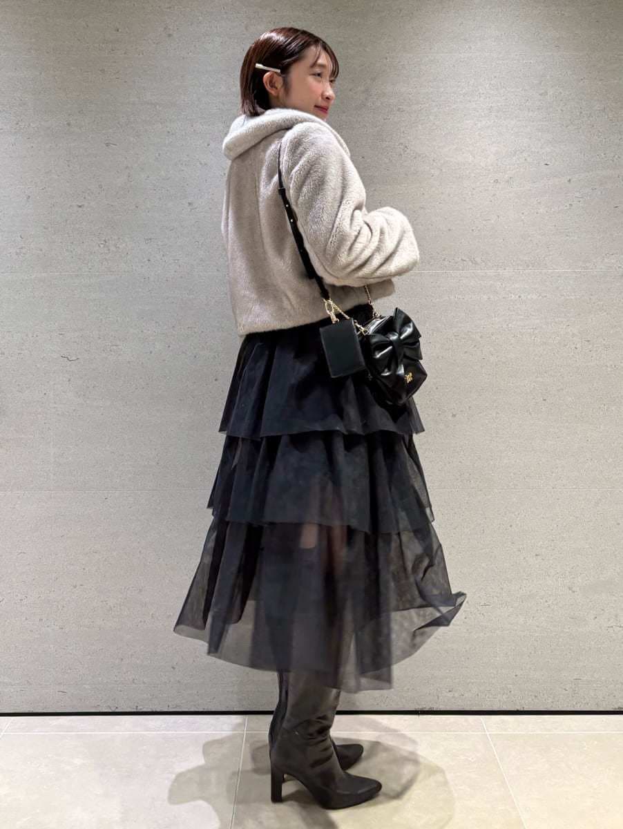 グレー系のブーツ、ベージュ系のステンカラーコート、ブラック系のスカートを着用したレディースの秋コーディネートの2枚目の写真
