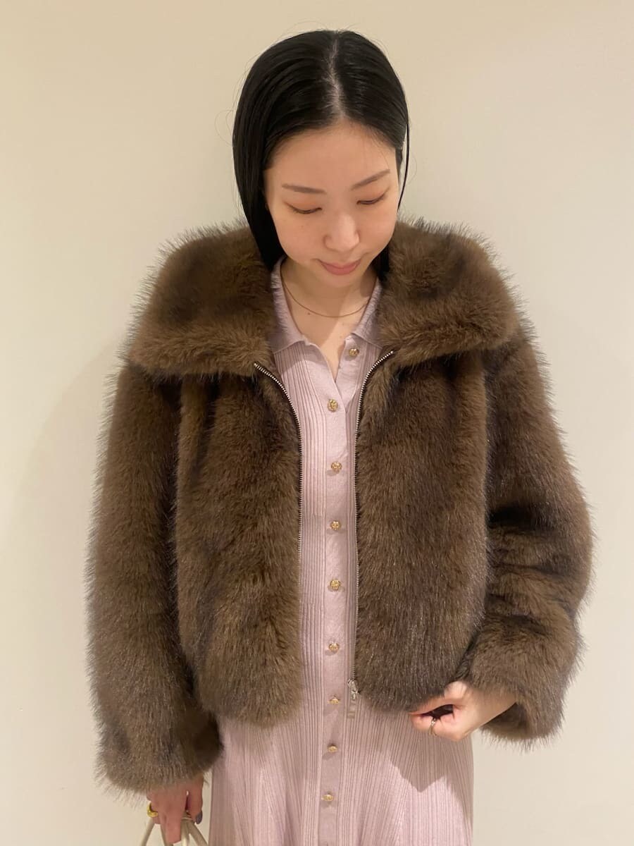 ブラウン系のチェスターコート、ピンク系のワンピース、ホワイト系のボストンバッグを着用したレディースの秋コーディネートの3枚目の写真