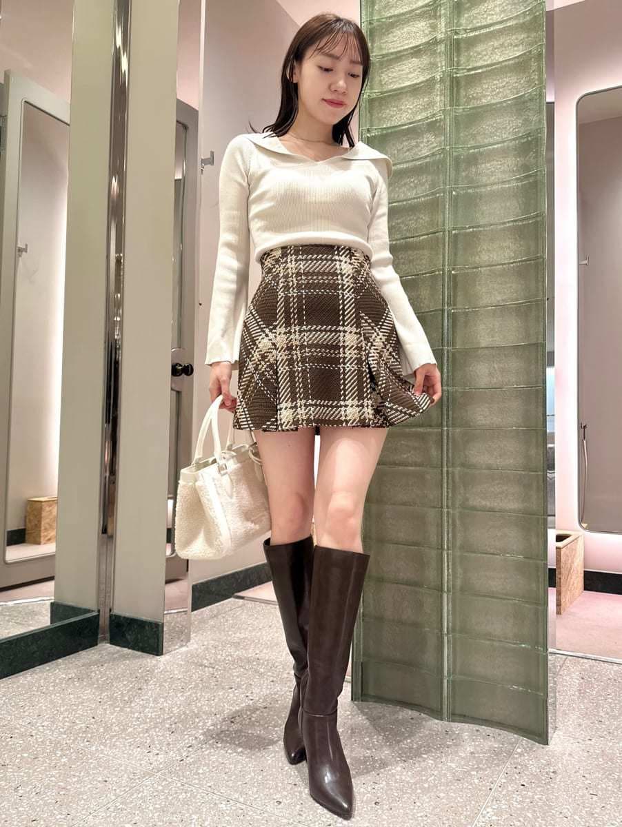 ホワイト系のニット/セーター、ブラウン系のスカート、ブラウン系のブーツを着用したレディースの秋コーディネートの2枚目の写真