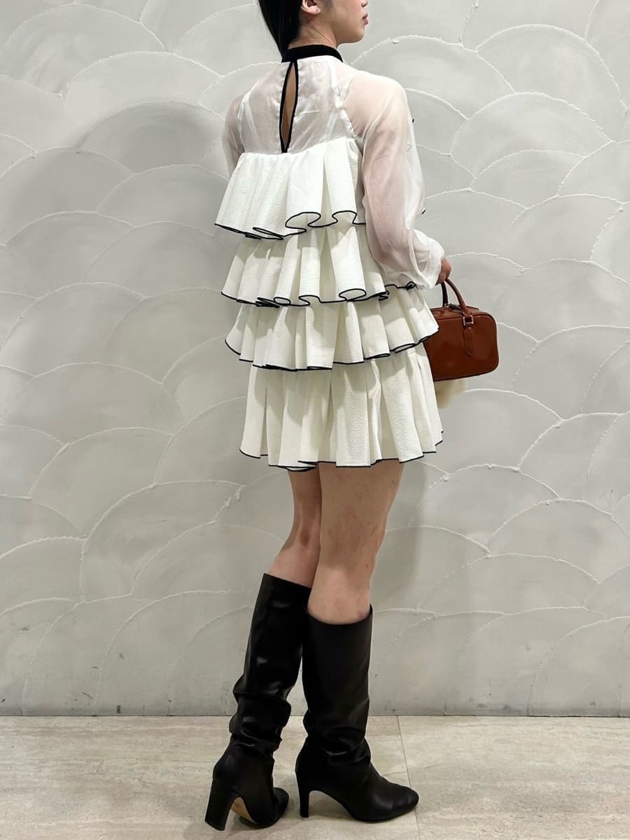 ブラウン系のボストンバッグ、ホワイト系のドレス、イエロー系のキーケース/キーアクセサリーを着用したレディースの冬コーディネートの4枚目の写真