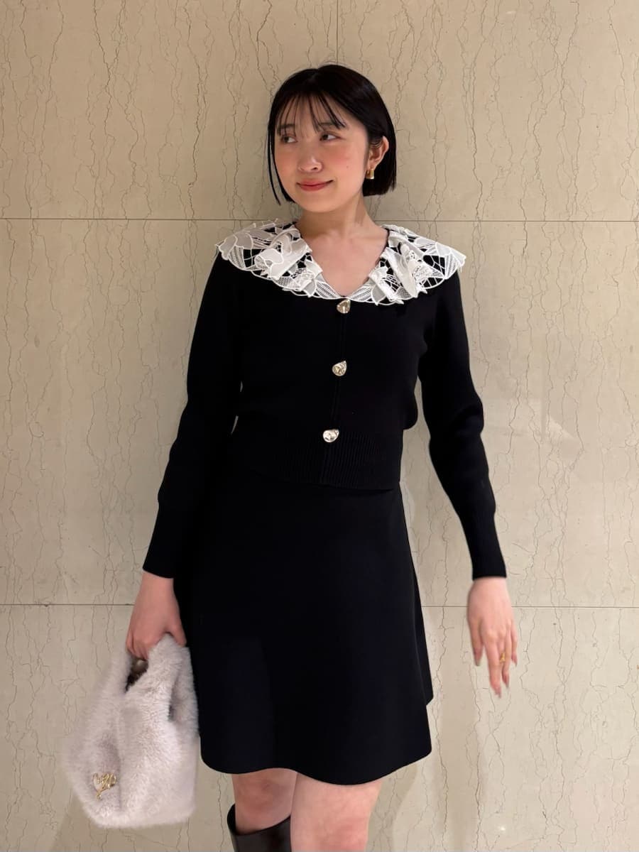 ブラウン系のブーツ、ホワイト系のハンドバッグ、ブラック系のワンピースを着用したレディースの冬コーディネートの3枚目の写真