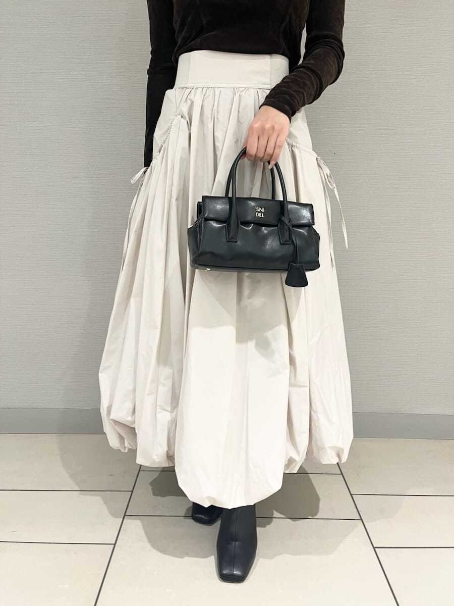 ベージュ系のスカート、ブラウン系のTシャツ/カットソー、ベージュ系のチェスターコートを着用したレディースの秋コーディネートの4枚目の写真