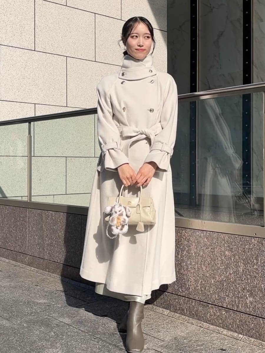 ホワイト系のチェスターコート、ホワイト系のワンピース、ホワイト系のボストンバッグを着用したレディースの秋コーディネートの4枚目の写真