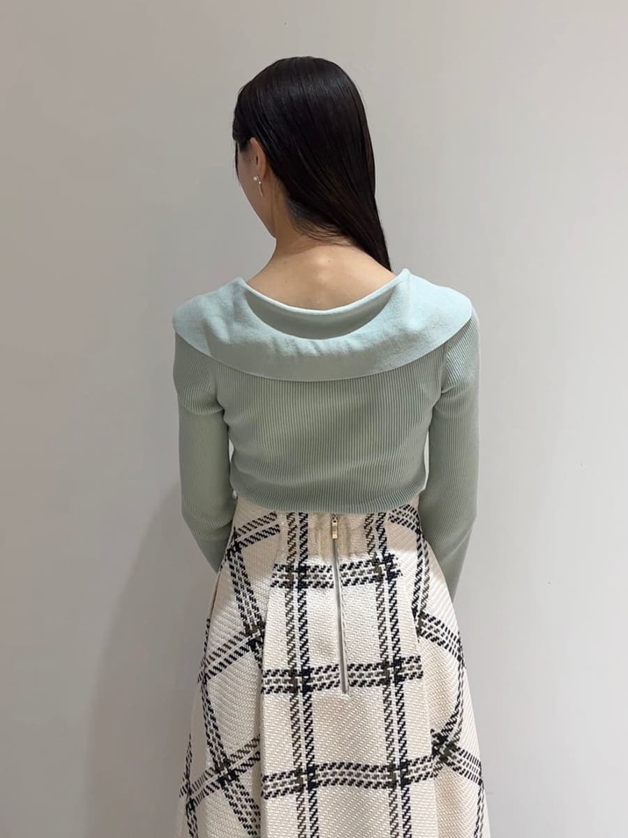 グリーン系のニット/セーター、ホワイト系のスカート、ブラック系のブーツを着用したレディースの秋コーディネートの7枚目の写真