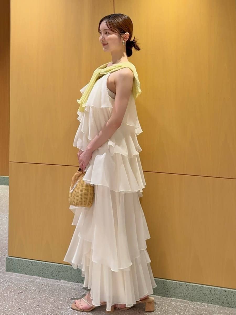 ブラウン系のかごバッグ、イエロー系のカーディガン/ボレロ、ホワイト系のドレスを着用したレディースの夏コーディネートの2枚目の写真