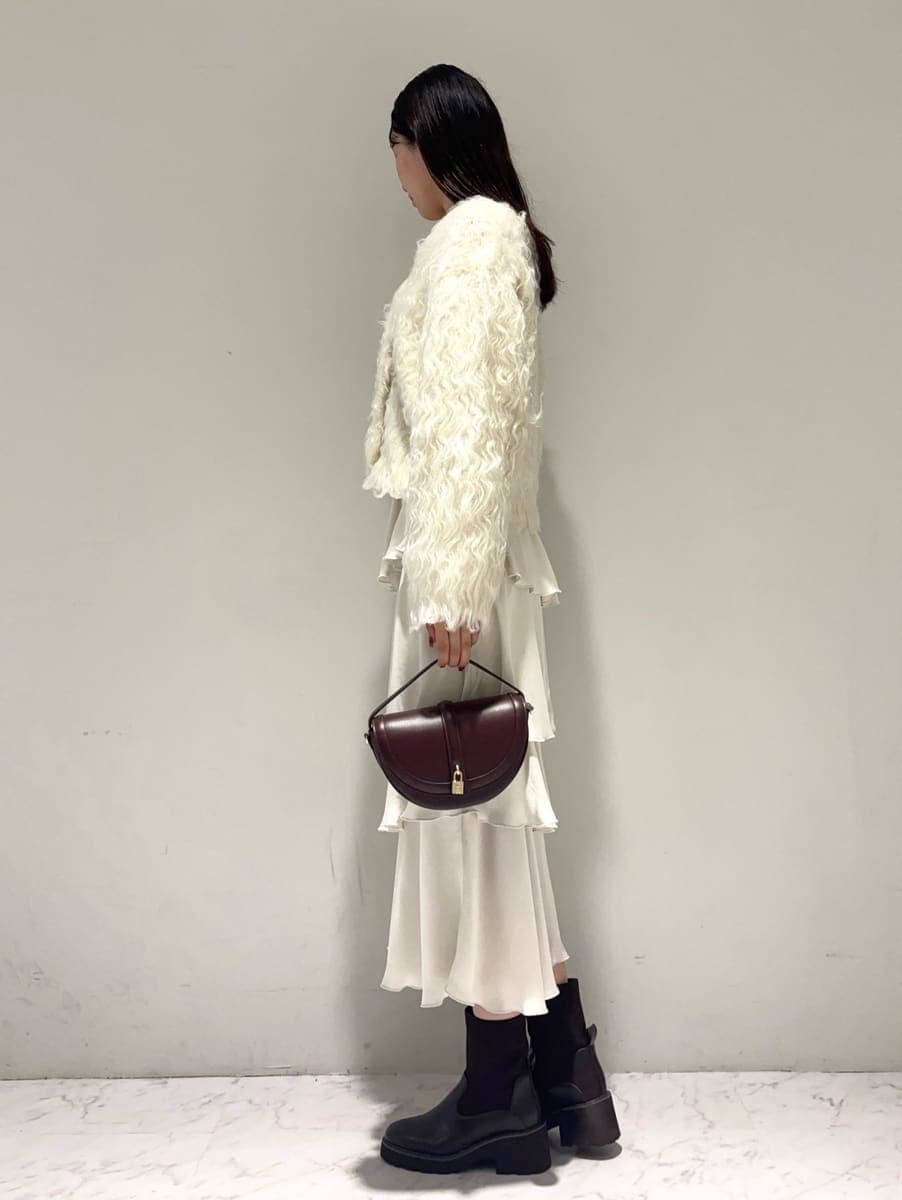 ホワイト系のカーディガン/ボレロ、ホワイト系のスカート、ブラウン系のハンドバッグを着用したレディースの秋コーディネートの3枚目の写真