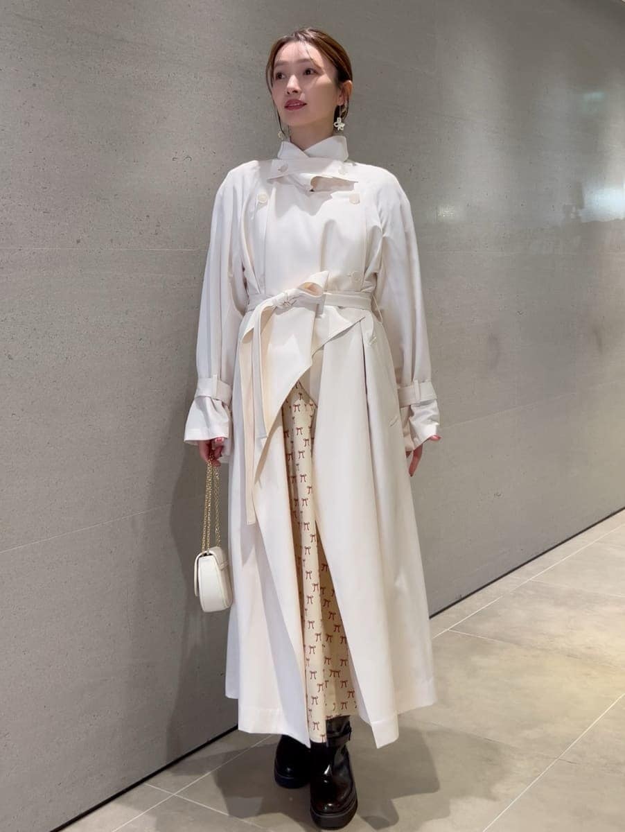 ホワイト系のトレンチコート、ベージュ系のワンピース、ホワイト系のショルダーバッグを着用したレディースの冬コーディネートの8枚目の写真