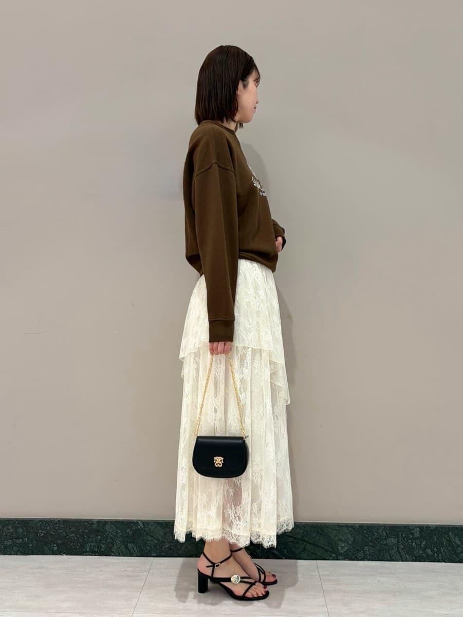 ホワイト系のスカート、ブラウン系のスウェット、ブラック系のショルダーバッグを着用したレディースの春コーディネートの3枚目の写真