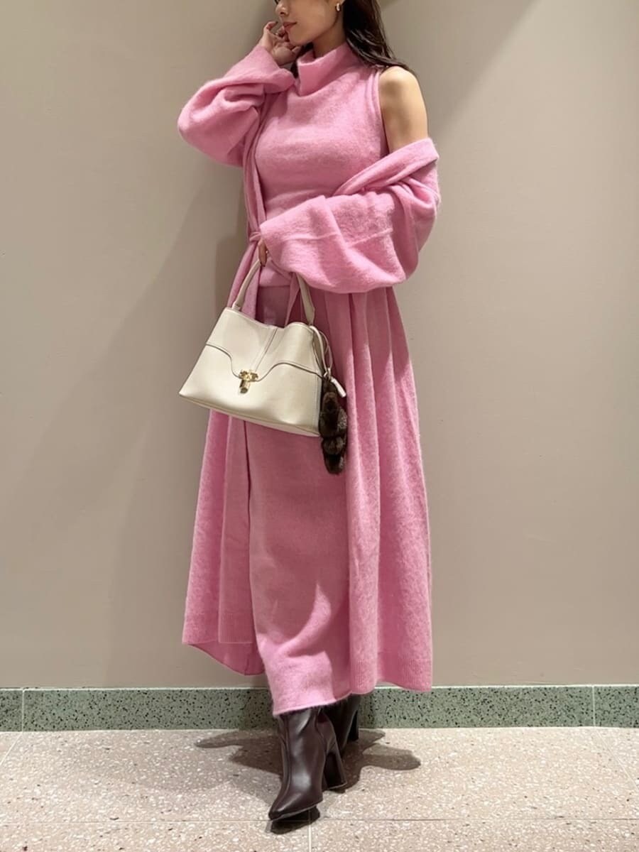 レッド系のブーツ、ピンク系のチェスターコート、ピンク系のワンピースを着用したレディースの冬コーディネートの2枚目の写真