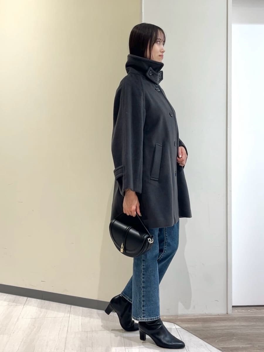 グレー系のステンカラーコート、レッド系のニット/セーター、ブルー系のデニムパンツを着用したレディースの秋コーディネートの8枚目の写真