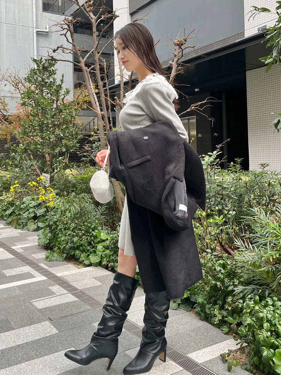 ブラック系のチェスターコート、グレー系のワンピースを着用したレディースの冬コーディネートの9枚目の写真
