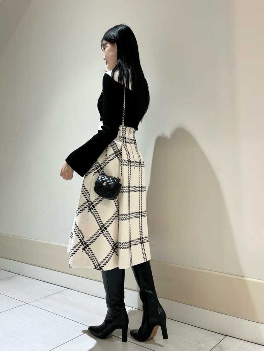 ブラック系のニット/セーター、ホワイト系のスカート、ブラック系のショルダーバッグを着用したレディースの秋コーディネートの2枚目の写真