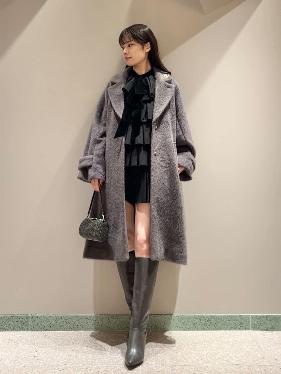 グレー系のブーツ、グレー系のチェスターコート、ブラック系のドレスを着用したレディースの冬コーディネートの2枚目の写真