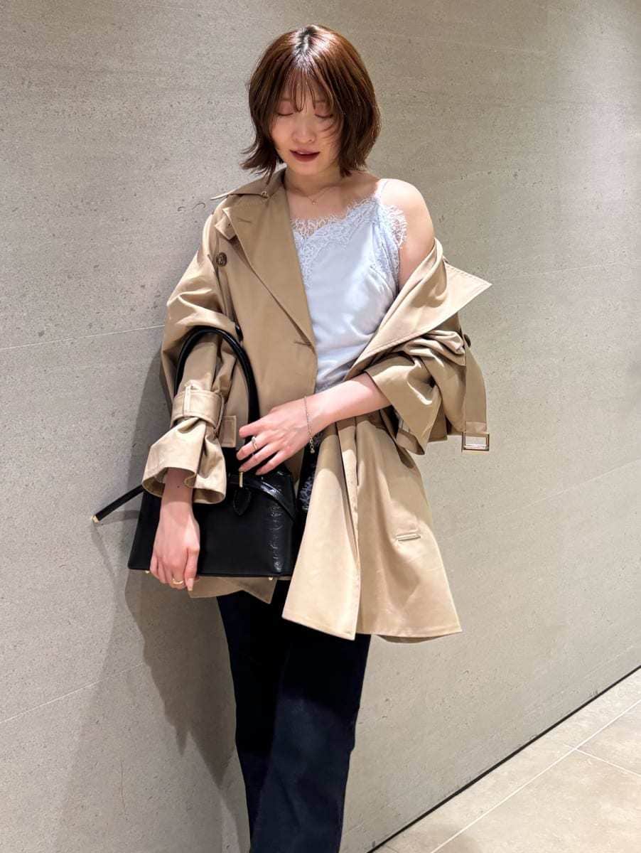 ブルー系のデニムパンツ、ベージュ系のトレンチコート、ブルー系のキャミソールを着用したレディースの秋コーディネートの5枚目の写真