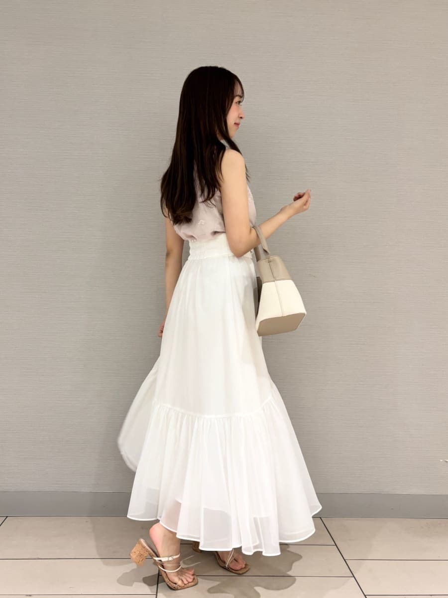 ベージュ系のハンドバッグ、ホワイト系のスカート、その他のサンダルを着用したレディースの夏コーディネートの2枚目の写真